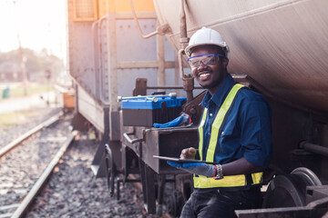 African machine engineer technician wearing a helmet, groves and safety vest is using a wrench to...