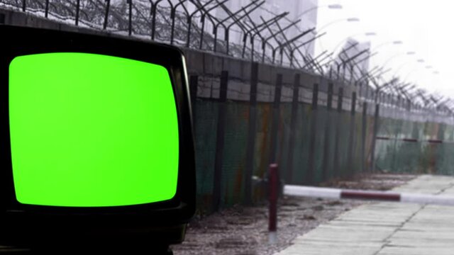 Old Television Set with Green Screen near a Wall with Barbed Wire Fence. You can replace green screen with the footage or picture you want. You can do it with “Keying” effect in After Effects. 4K.