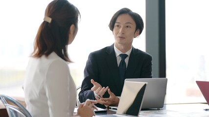 Obraz premium オフィスで打ち合わせをする男女