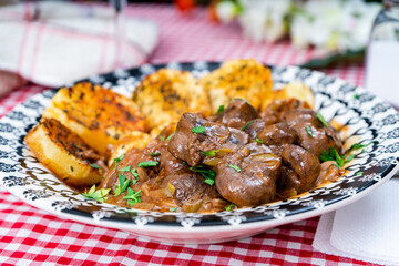 Beef kidney, leek and onion stew with Spanish style potatoes served on a vintage plate.