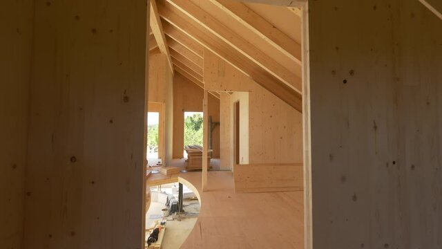 CLOSE UP: View of the beautiful unfinished interior of a prefabricated lumber house in the sunny countryside. Gorgeous shot of the spacious top floor of a glued-laminated house under construction.