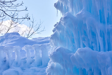 Ice castle covered in snow and melting slowly in the winter sun