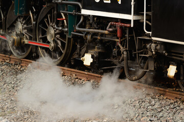 Selective focus on wheel arrangement and treadle with steam and pressure is released from Pacific type steam locomotives on track.