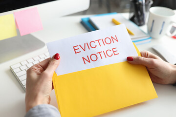Woman sitting at table and holding eviction letter closeup