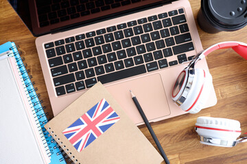 Headphones and english textbooks lying on laptop keyboard closeup