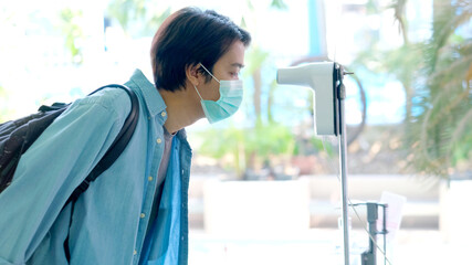 University man wearing protective mask while scan thermometer contectless before entrance to campus, coronavirus prevention