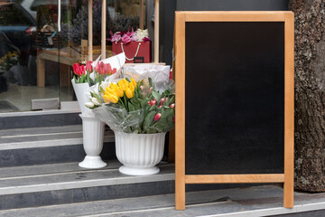 Signboard on the street. Empty menu board stand. Restaurant sidewalk chalkboard sign board. Freestanding A-frame blackboard near flower shop. Copyspace for text, selective focus