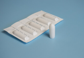 Suppository for anal or vaginal use on a blue background. Candles for the treatment of hemorrhoids,...