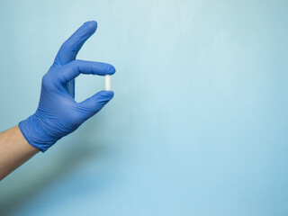 the rectal candle is held by a hand in a blue medical glove