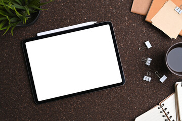 Top view of mock up digital tablet, stylus pen, notebook, coffee cup and sticky note on brown...