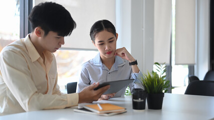 Young female employee working with her boss in modern office.