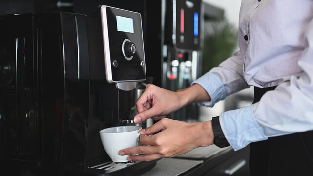 Close up view of businessman making coffee from coffee machine in the office.