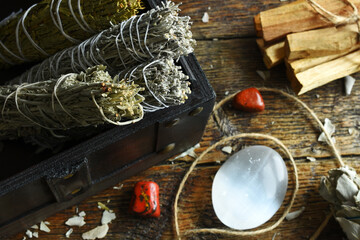 A close up image of white sage smudge bundles with selenite and red jasper crystals. 