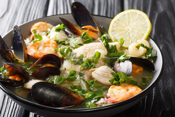 Seafood shellfish soup of mussels, Shrimps, clams and other shellfish typical chilean dish Paila marina or Mariscal close-up in a bowl on the table. horizontal