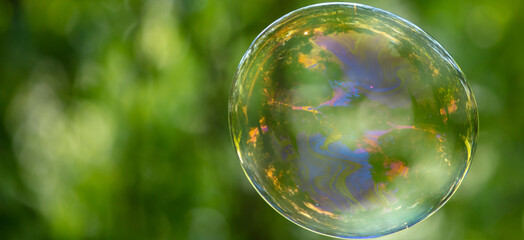 A large soap bubble flies in the park.