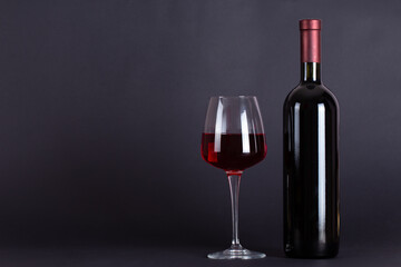 Sealed bottle of red wine and glass on a lilac background.With space for text.