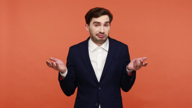 I don't know. Puzzled clueless businessman shrugging shoulders, bearded man with raised arms and confused face, has uncertain confused expression. Indoor studio shot isolated on orange background.