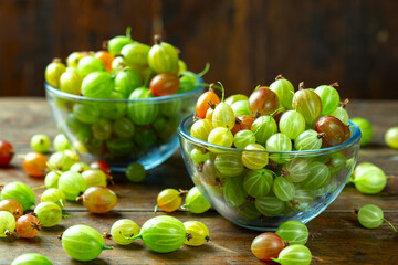 Ripe gooseberry in a glass plate, place for text, top view, summer harvest of berries.