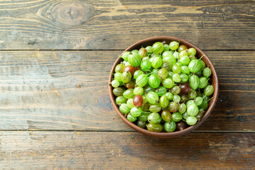 Ripe gooseberry in plate, place for text, top view, summer harvest of berries.