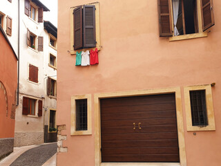Fototapeta na wymiar Italian flag in the form of t-shirts that dry on a rope under the window.