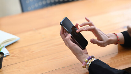 Close up view of woman pointing on screen of smart phone while sitting in office.