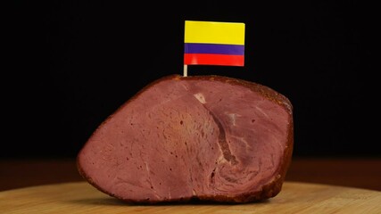 Person placing decorative Colombian flag toothpicks into piece of red meat. - Powered by Adobe