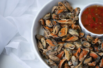 Half a plate of poached mussels with seafood sauce in white plate