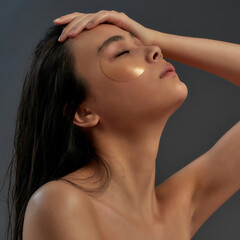 Naklejka premium Young beautiful asian half naked woman in bath towel with cosmetic eye patches touching her face while eyes closed