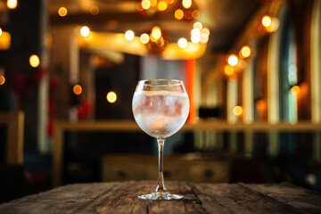 Glass of gin tonic cocktail with on the wooden desk with a blurry background