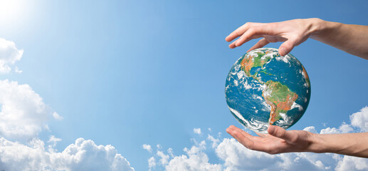 Hands holding a planet, earth on a background of nature blue sky with beautiful white clouds and sunlight.Sustain earth concept. Elements of this image furnished by NASA