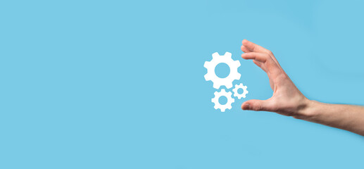 Male hand holding cog gears icon ,mechanism icon on virtual screens on blue background. Automation...