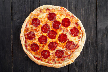 Top view on pepeproni pizza on the wooden background