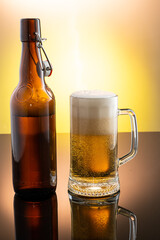 pouring beer into beer glass from bottle on yellow background