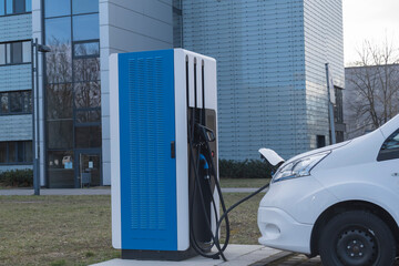 Ein weißer Transporter wird an einer E-Tankstelle elektrisch betankt