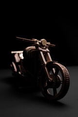 Fototapeta na wymiar Wooden toy motorcycle on a black background a close up