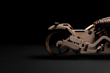 Fototapeta na wymiar Wooden toy-motorcycle designer on a black background
