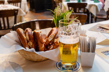 Classic German dinner of fried sausages with braised cabbage on large white plates with light beer, standing on table in restaurant interior.