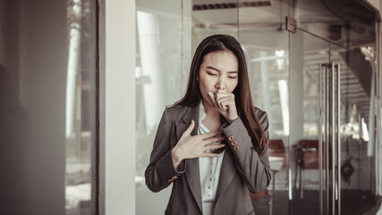 Young Asian women cough and cover their mouths with their hands to prevent drooling, young business woman is sick and infected with the virus, Coronavirus symptom concept.