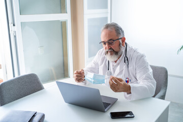 Doctor has a video conference with a patient who shows a surgical mask to avoid contagion by Covid-19