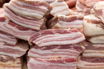 Pieces of salted lard. End view. Red meat layers, spices.