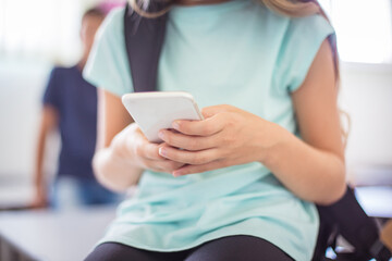  School girl using phone in classroom.