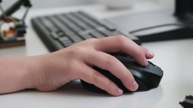 hands of a boy with a mouse at the computer