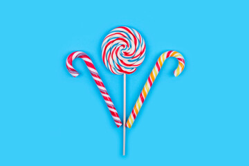 Colorful lollipop and sugar canes on light blue background