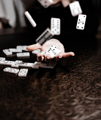 Cropped image of woman playing dominoes at table. Young adults playing the game of Domino with emotions. Scatter or throw away the pieces.