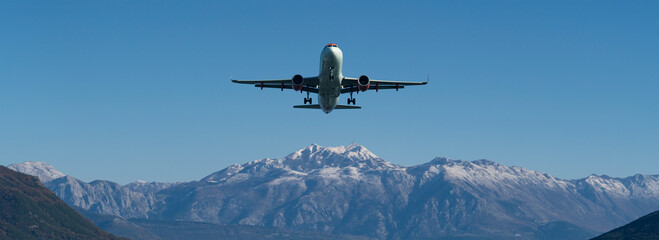 The plane is landing at the airport against the background of mountains in the snow