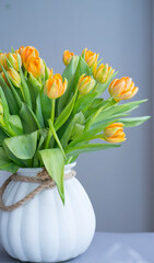 White vase with a large bouquet of peach tulips on a gray background
