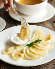 Closeup on eating russian dumplings vareniki with sour cream
