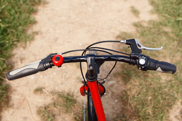 Naklejka na ściany i meble Bicycle handlebars on a trail background. Cycling in nature