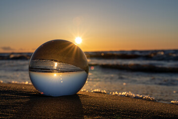 Fototapeta na wymiar a glowing sunset can be seen through a glass ball. The sun shines along the edge of the ball