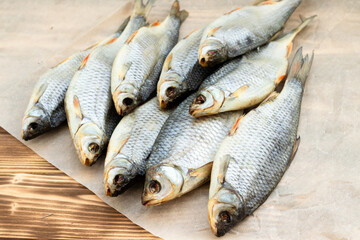 fish dry, roach, lies on a wooden table on paper.
